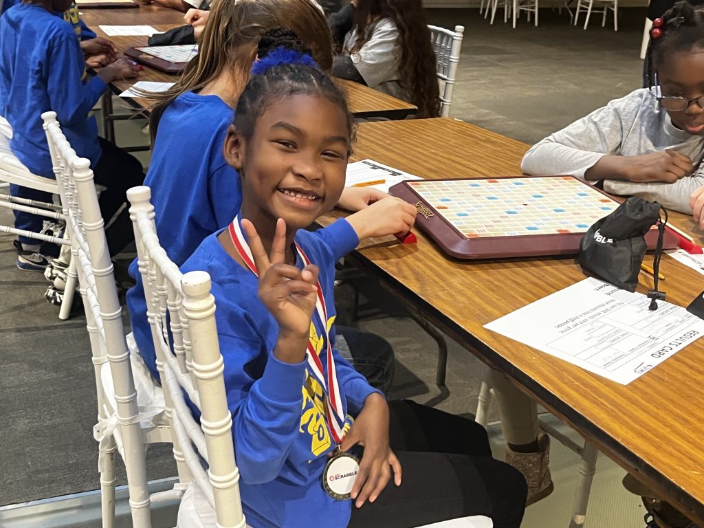 Scrabble student poses with peace sign during Scrabble event